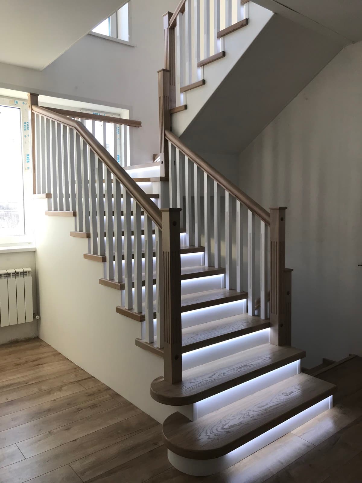 Вид на лестницу на металлокаркасе с подсветкой с первого этажа