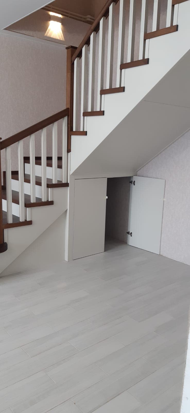 Первый марш обшит панелями МДФ в белой эмали, предусмотрена кладовая