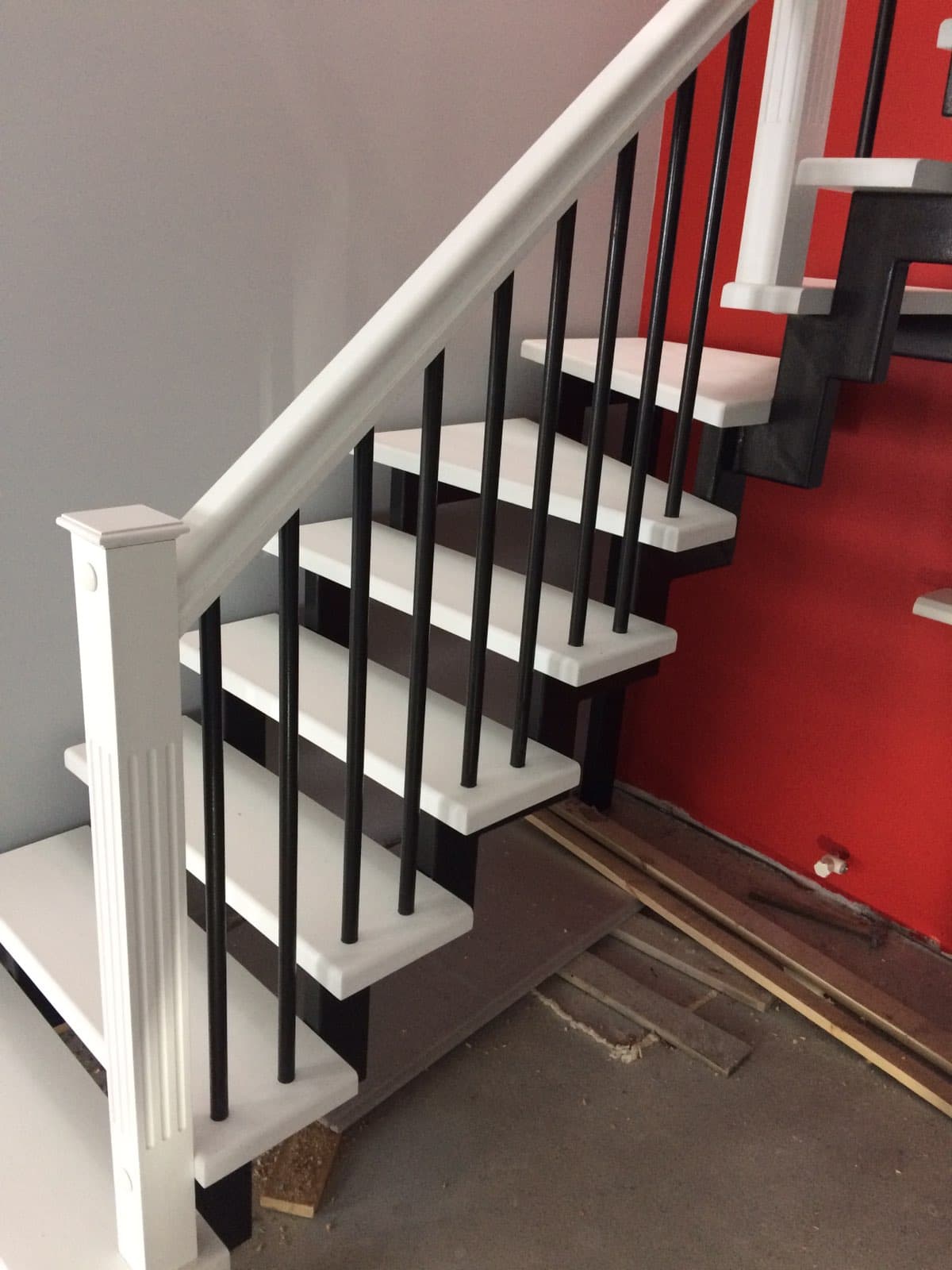 Ограждение с черными трубами из металла и деревянными поручнями на первом марше лестницы