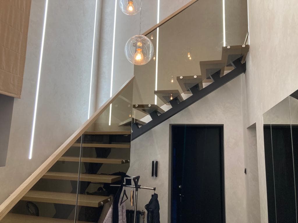 Лестница на монокосоуре со стекляным ограждением в интерьере.